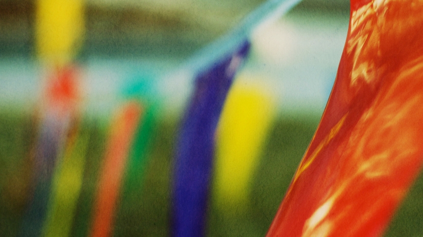 Multicolored plastic flagging blurs into the distance; the overall effect is reminiscent of Tibetan prayer flags